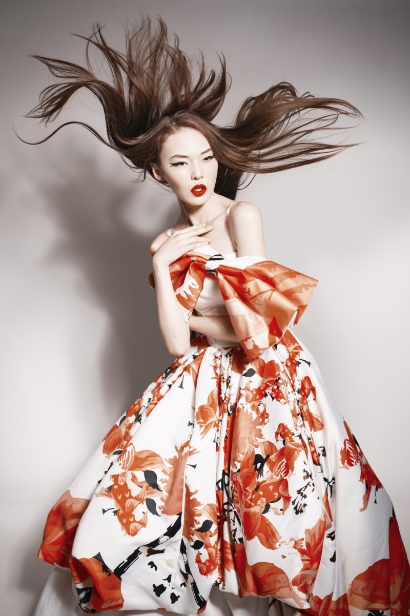 young beautiful asian brunette in gorgeous dress, motion shot, flying hair